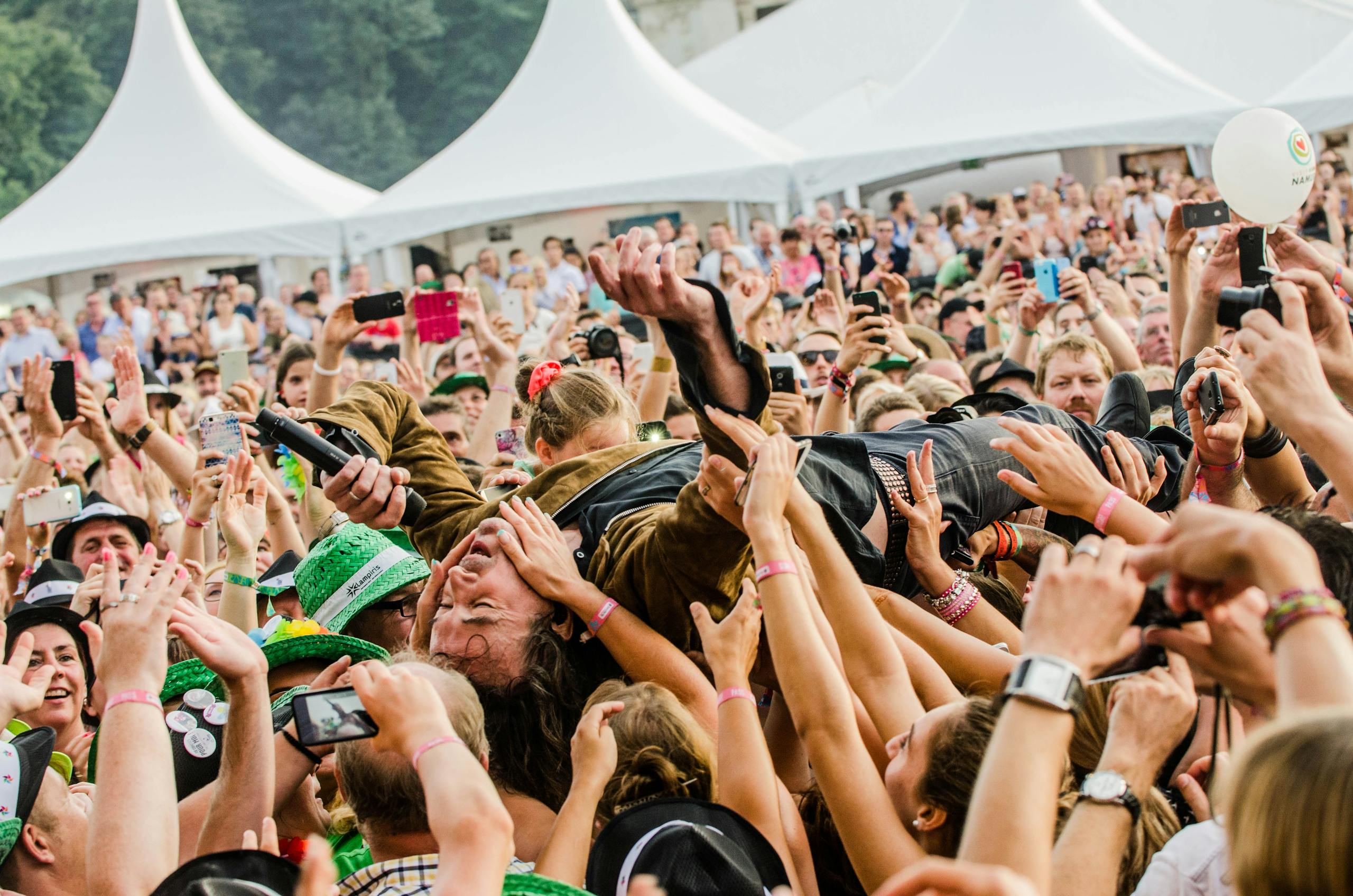 A lively crowd at a music festival supporting a crowd surfing performer.