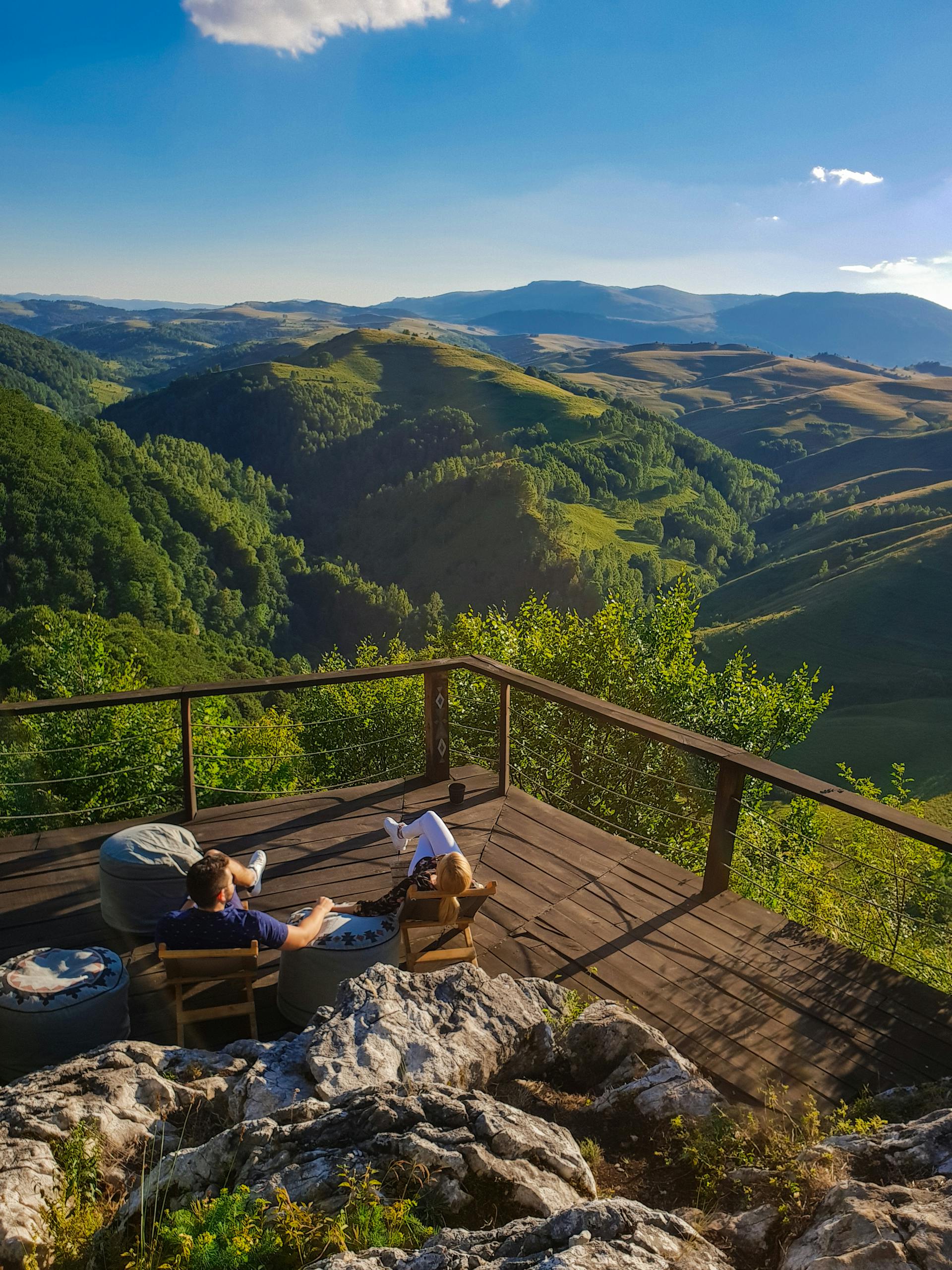 Couple enjoying a tranquil view of Alba's rolling hills from a wooden deck.