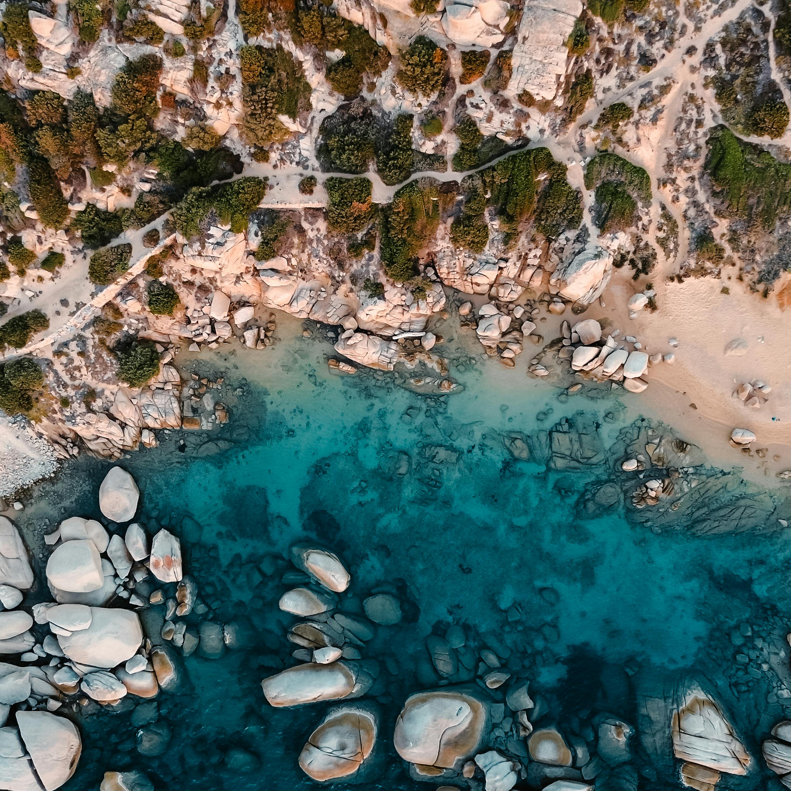 Stunning aerial perspective of Porto Pollo with turquoise waters and rugged rocks in Sardinia, Italy.